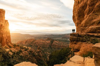 Genç heteroseksüel çift Sedona 'daki Katedral Rock' tan dramatik gün batımında el ele tutuşuyorlar..