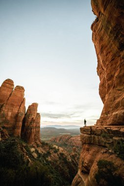 Günbatımında Sedona Arizona 'da Katedral Kaya Bakış Açısı' ndan ayakta duran kadının geniş açılı dikey görüntüsü.