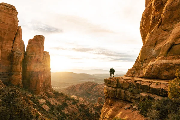 stock image Young couple stand in amazement on top of Cathedral Rock in Sedona.