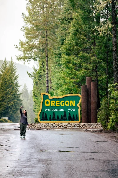 stock image Woman smiles takes selfie with Oregon welcomes you sign on Redwood Highway.