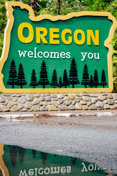 stock image Closeup image of Oregon Welcomes You Sign on US-199 with reflection in puddle.