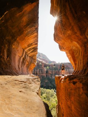 Gizli metro mağarası Boynton Canyon Sedona yalnız bayan sırt çantalı güneş yıldızı ile uçurumun kenarında poz veren.