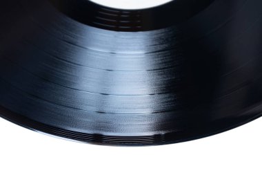 Dönen bir vinil plak ışığı yansıtır, parlak yüzeyini gösterir ve sessiz bir stüdyo ortamında klasik müzik çalarken karmaşık oyuklar oluşturur..
