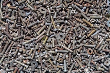 Yüzeye saçılmış çeşitli metal yıkama, vida, vida, somun ve cıvatalardan oluşan kaotik çeşitliliğin yakın görüntüsü farklı boyutları ve dokuları gösteriyor. İnşaat, mühendislik veya DIY işçiliği ile ilgili projeler için mükemmel.