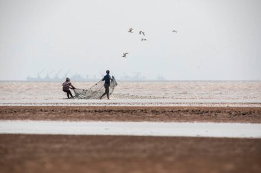Geleneksel balıkçılar kıyıda balık yakalar.