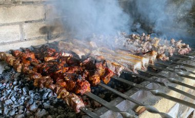 Farklı etlerden şiş kebap. Taş ızgarada metal şişler.