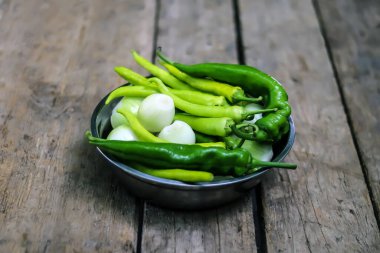 Köy masasındaki kasede taze biber ve soğan kafaları.