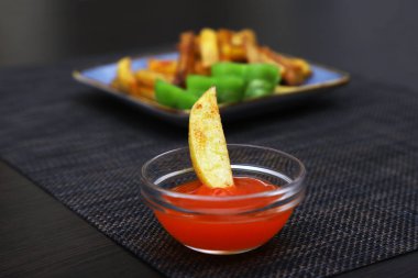 Bulanık bir arka planda ketçapla bir konteynırda bırakılmış patates kızartması. Yakın plan.