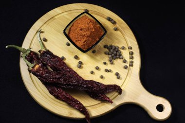 Karabiberli puantiyeli siyah ışık altında servis panosuna serpiştirilmiş karabiber ve kurutulmuş biber. Yakın plan.