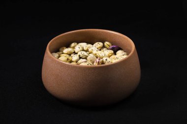 Siyah arka plandaki masada duran bir fincanda fasulye taneleri. Sığ alan derinliği