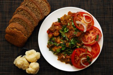 Taze bitkilerle pişirilmiş sebze salatası. Bir tabak patlıcan havyarı, masada tuzlu karnabahar ve kahverengi ekmek.