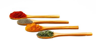 Zemin zerdeçal, kekik otu, beyaz arka planda ahşap kaşıklarda siyah ve kırmızı biber. Yakın plan.