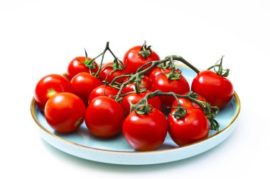 Beyaz arka planda mavi tabakta vişneli domates. Sığ alan derinliği