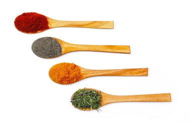 Zemin zerdeçal, kekik otu, beyaz arka planda ahşap kaşıklarda siyah ve kırmızı biber. Yakın plan.