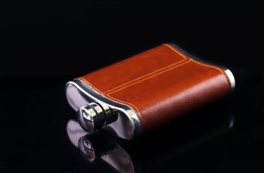 Siyah bir arka planda, deri süslemeli alkol şişesi. Yakın plan.