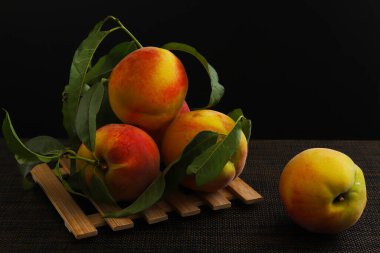 Olgun şeftaliler, koyu ışıkta dallarla. Yakın plan.