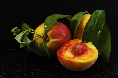 Kesik şeklinde olgun şeftaliler ve karanlık bir ışık altında bir dal. Yakın plan.