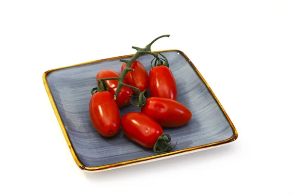 stock image Cherry tomatoes with a branch on a plate on a white background. Close-up