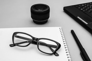 Gri bir fotoğraf muhabirinin masasında siyah çerçeveli optik gözlük. Sığ alan derinliği