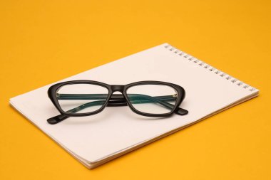 Turuncu arka planda siyah çerçeveli optik gözlük. Sığ alan derinliği