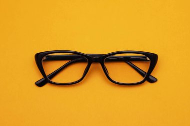 Turuncu arka planda siyah çerçeveli diyopterli gözlükler. Yakın plan.