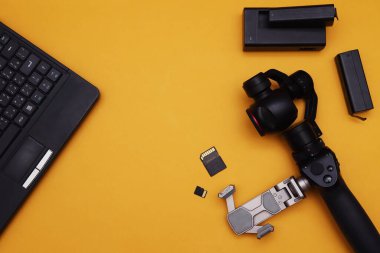 Minyatür mekanik dengeleyicili kamera ve turuncu arka planda dizüstü bilgisayar..