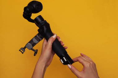 Kadınların elinde minyatür dengeleyicili kamera şarj etmek için bataryayı çıkarıyor.