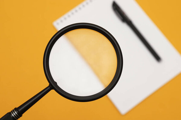 Лупа или увеличительное стекло на оранжевом фоне. Мелкая глубина резкости