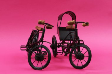 Dekoratif hediye bisikleti. Pembe arka planda üç tekerlekli klasik bir araba. Sığ alan derinliği