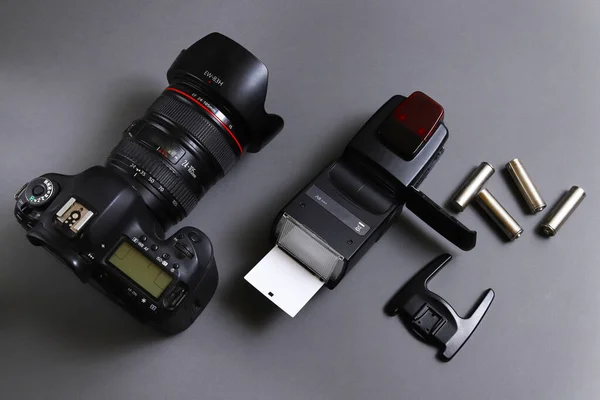 Photojournalist\'s desk. On-camera flash with a digital camera on a gray background