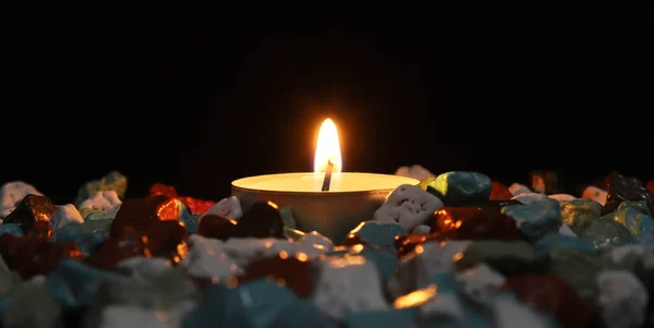 Eine Brennende Kerze Zwischen Kieselsteinen Auf Schwarzem Hintergrund — Stockfoto