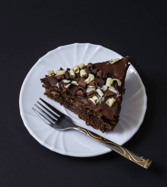 Koyu ışığın altında tabakta çikolatalı pasta. Sığ alan derinliği