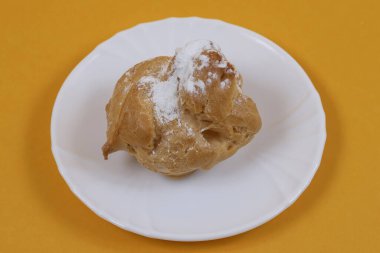 Turuncu arka planı olan beyaz bir tabakta pasta. Sığ alan derinliği