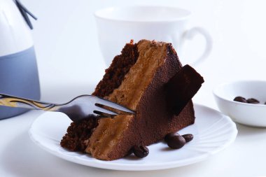 Parlak ışıkta bir tabağın üzerindeki çikolatalı tatlı pastasının bir parçası. Sığ alan derinliği