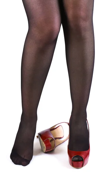 白い背景に赤いハイヒールの靴を持つ暗いストッキングで細い女性の足のペア — ストック写真
