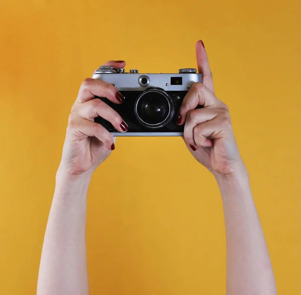 stock image retro camera in female hands on yellow background