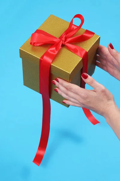 Kobiece Ręce Rozpakowywanie Złotego Kraft Papier Pudełko Czerwoną Wstążką Łuk — Zdjęcie stockowe