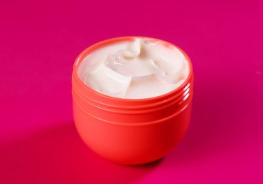 Kırmızı bir kapta narin bir el kremi. Yaşlanma önleyici krem yakın plan.