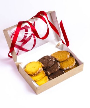 Kırmızı kurdeleli bir hediye kutusunda üç çeşit kurabiye. Yakın plan.