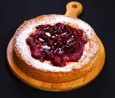 Ahududu reçelli iştah açıcı pasta ve ahşap bir tahtanın üzerinde koyu renkli ışıkta pudra şekeri. Yakın plan.