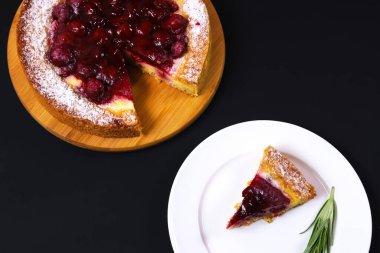 Dilimlenmiş ahududu turtası, siyah bir masada beyaz bir tabakta. Yakın plan.