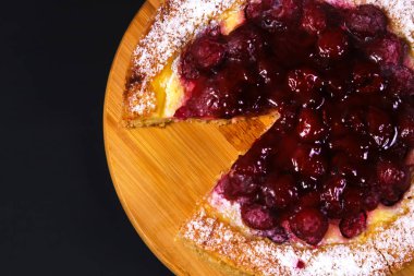 Ahududu reçelli iştah açıcı pasta ve ahşap bir tahtanın üzerinde koyu renkli ışıkta pudra şekeri. Yakın plan.