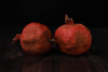 Karanlık bir masada, karanlık bir ışığın altında iştah açıcı nar. Yakın plan.
