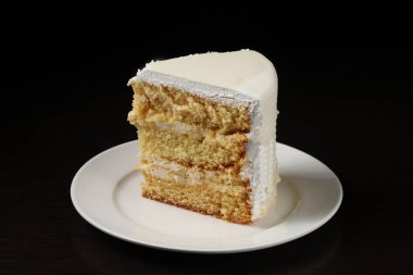 Koyu ışık altında badem ezmeli beyaz pasta. Yakın plan.