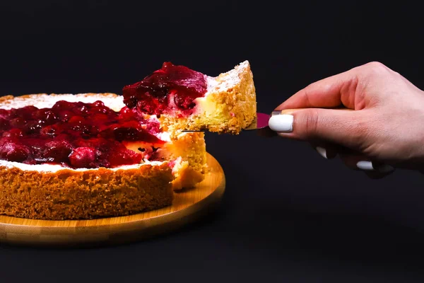 Sliced pie with strawberry jam and portion in female hand. Close-up