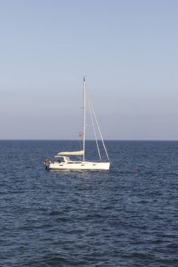 Ufuktaki denizde küçük bir yelkenli gemi.