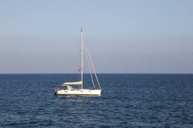 Ufuktaki denizde küçük bir yelkenli gemi.