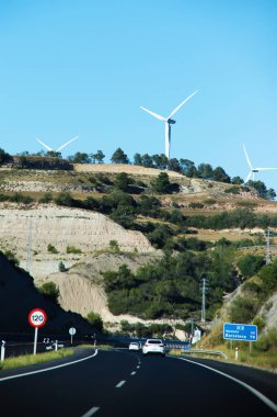 İspanya 'da dağ tepelerinde trafik işaretleri ve rüzgar türbinleri olan otoyol