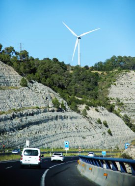 Barselona, İspanya - 10 Temmuz 2024: Dağların tepesinde trafik ışıkları ve rüzgar türbinleriyle İspanya 'da otoyol