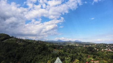Tropikal dağların ve mavi gökyüzü olan yerleşim alanlarının doğal manzarası.